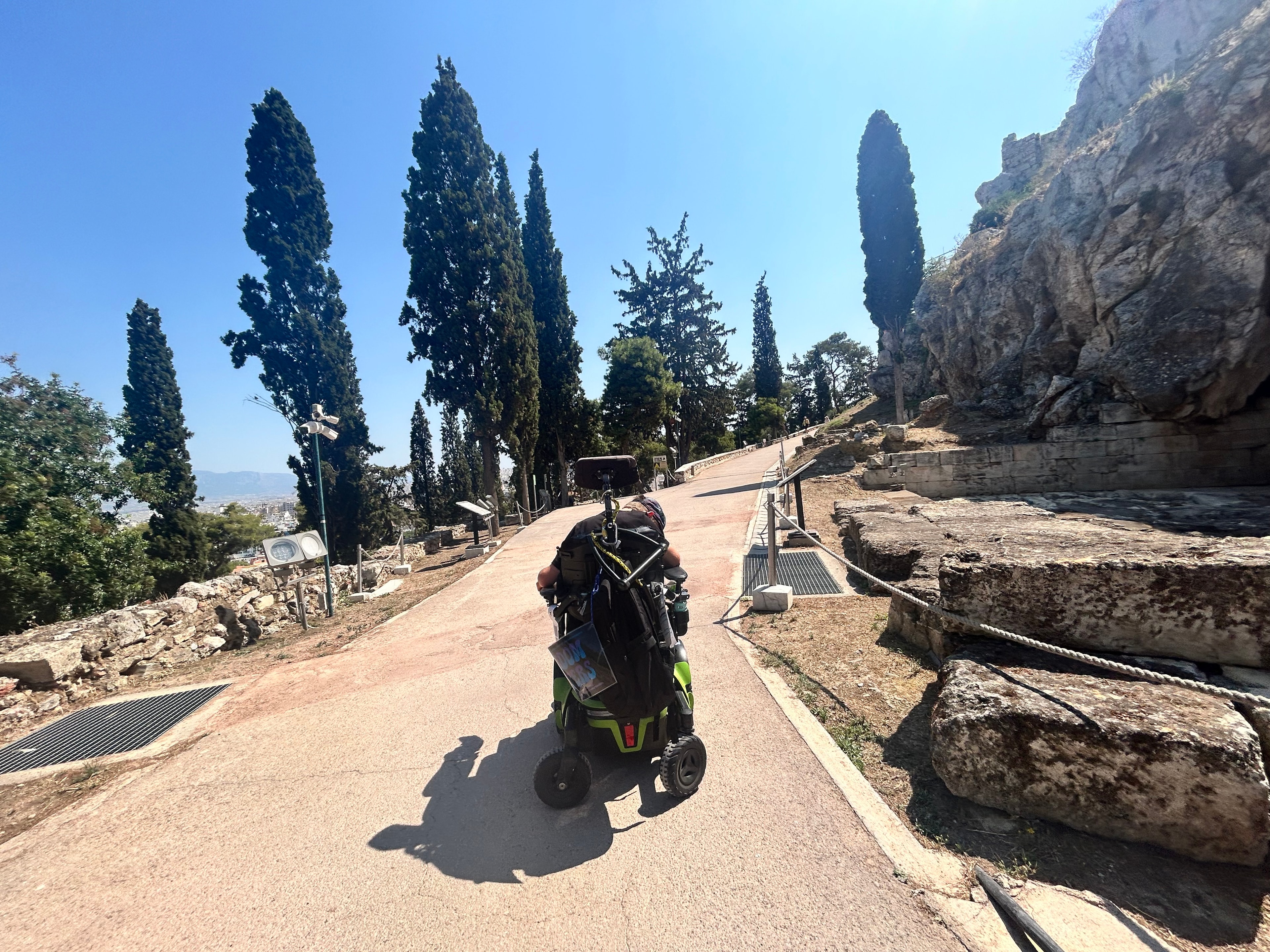 Wide smooth accessible paved path at the Acropolis with a wheelchair user rolling along it